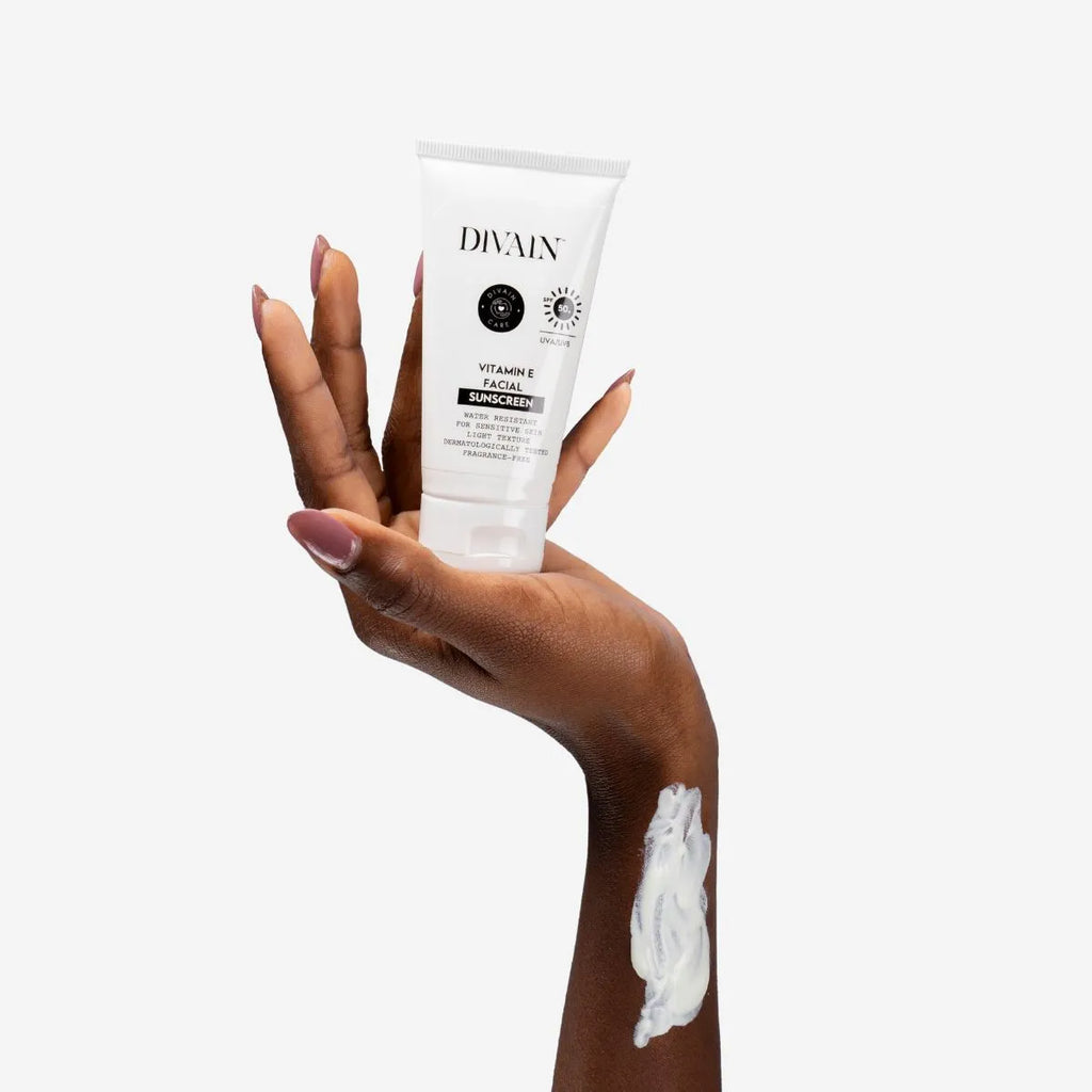 Divain Care facial sunscreen with vitamin E, held in the hand and applied to the skin.