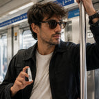 Man applying a divain mini perfume on the underground